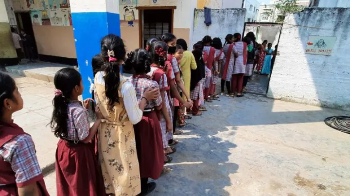 Photo of a girl student walking away from a school with no toilet facilities